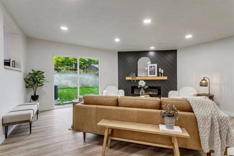 Bright living room addition with dark shiplap fireplace wall, linear gas fireplace, leather sofa, and sliding glass door to backyard — Utah living room addition by CasaMás Construction